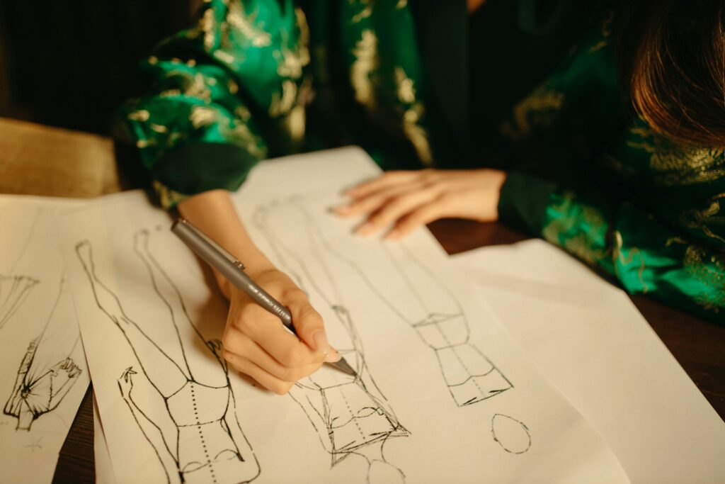Close-up of a fashion designer sketching clothes in an atelier, highlighting creativity and craftsmanship.
